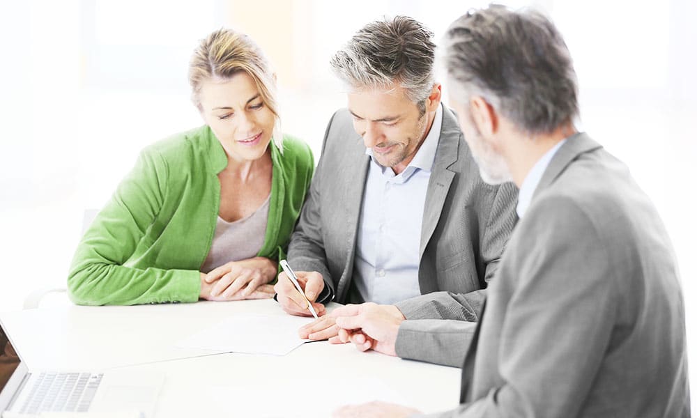 Business team discusses while writing with pen on paper