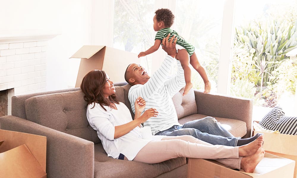 Middle aged couple playing with baby while on couch