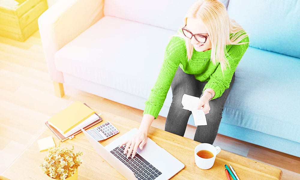 Woman drinking tea and working on computer in living room