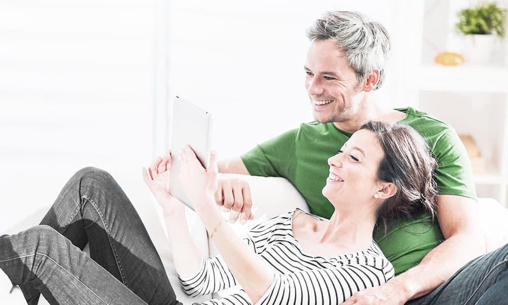 Couple lays on couch while on iPad