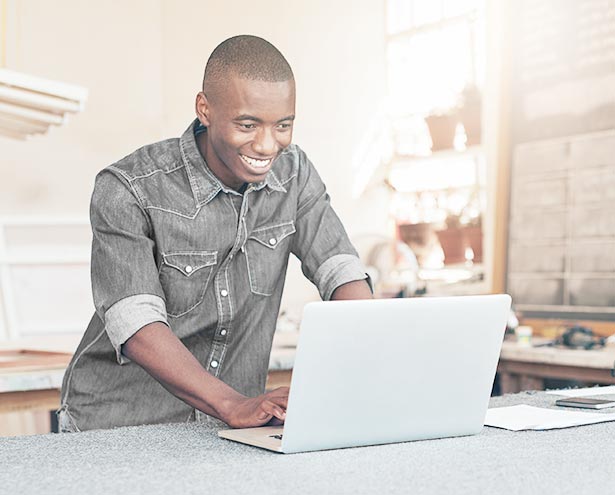Man is smiling while looking at laptop