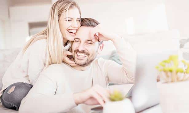 Young couple having lots of fun while on computer and smiling