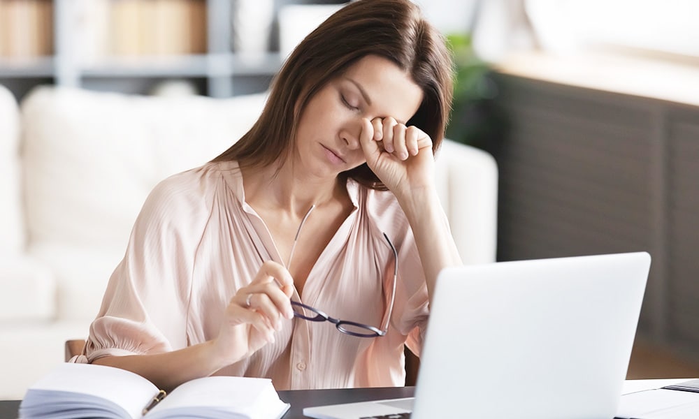 Woman stressed out and rubbing eye while dealing with tax debt