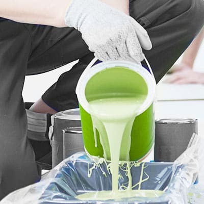 Man pouring green paint into bucket